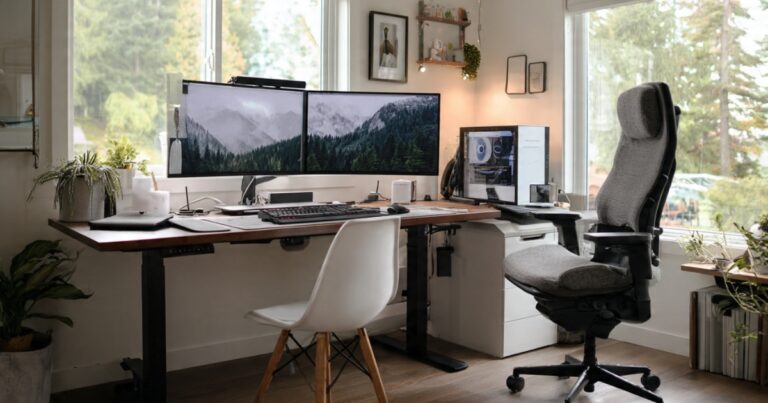 Ergonomic home office setup featuring split keyboard, vertical mouse, adjustable monitor arm, and ergonomic office chair on wooden desk
